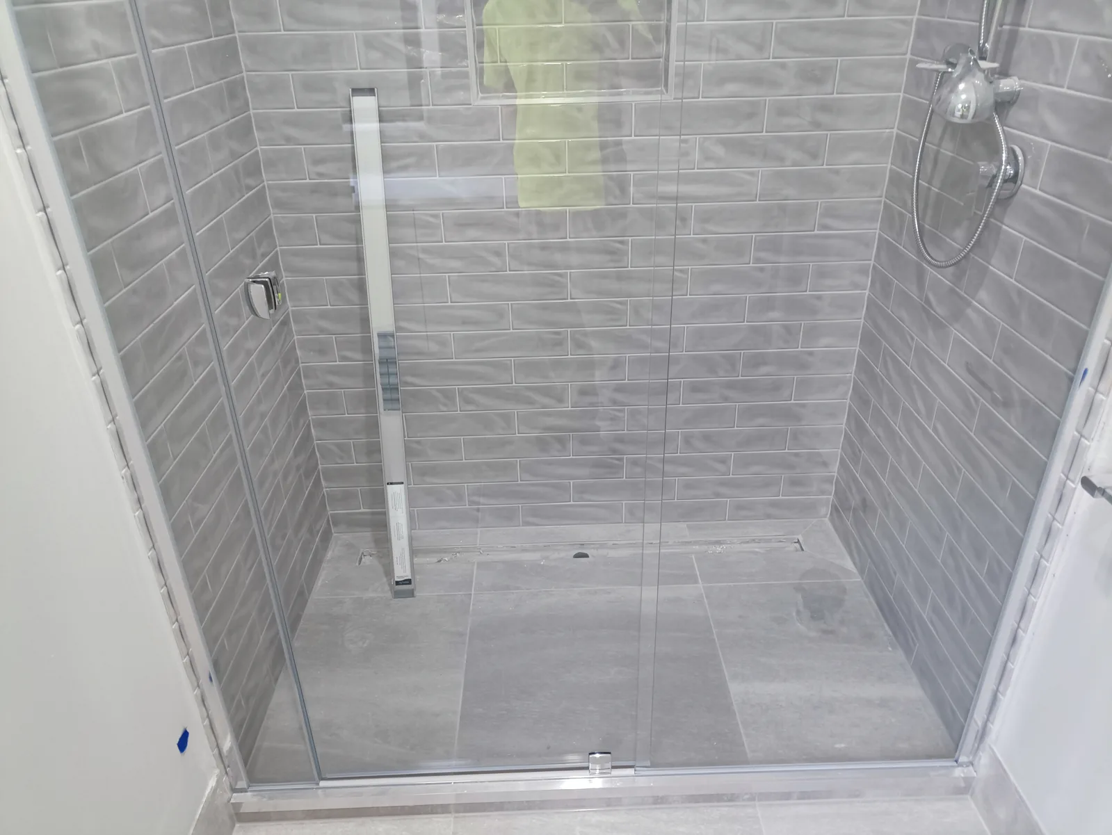 Frameless glass shower screen sealed to grey subway tiles, Melbourne