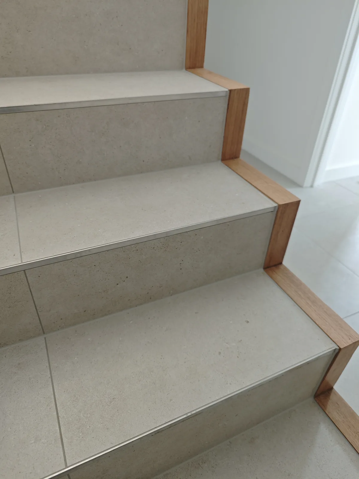 Stone stair tread with timber edge trim and precise sealing, Melbourne